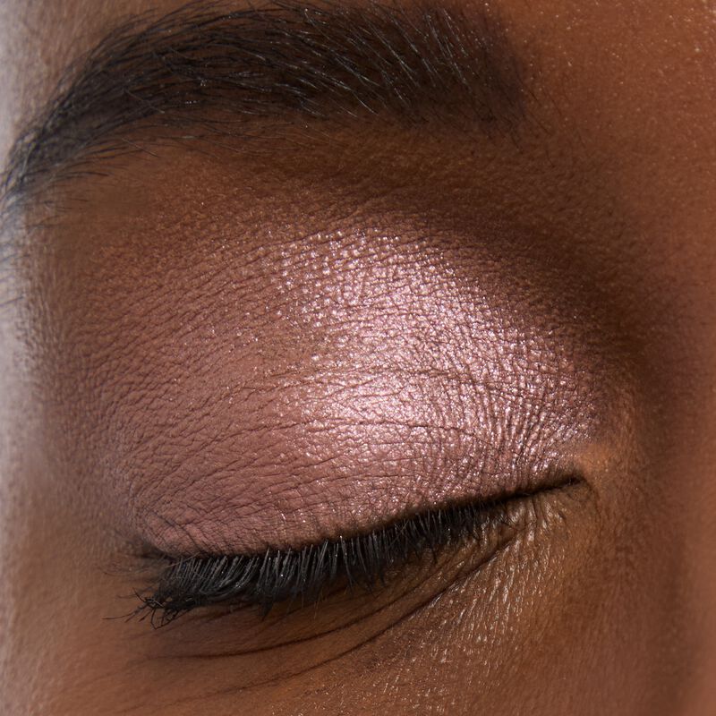 Deep skinned model wearing Mary kay Eye Shadow Sticks in shades Pink Prisms and Lunar Rose
